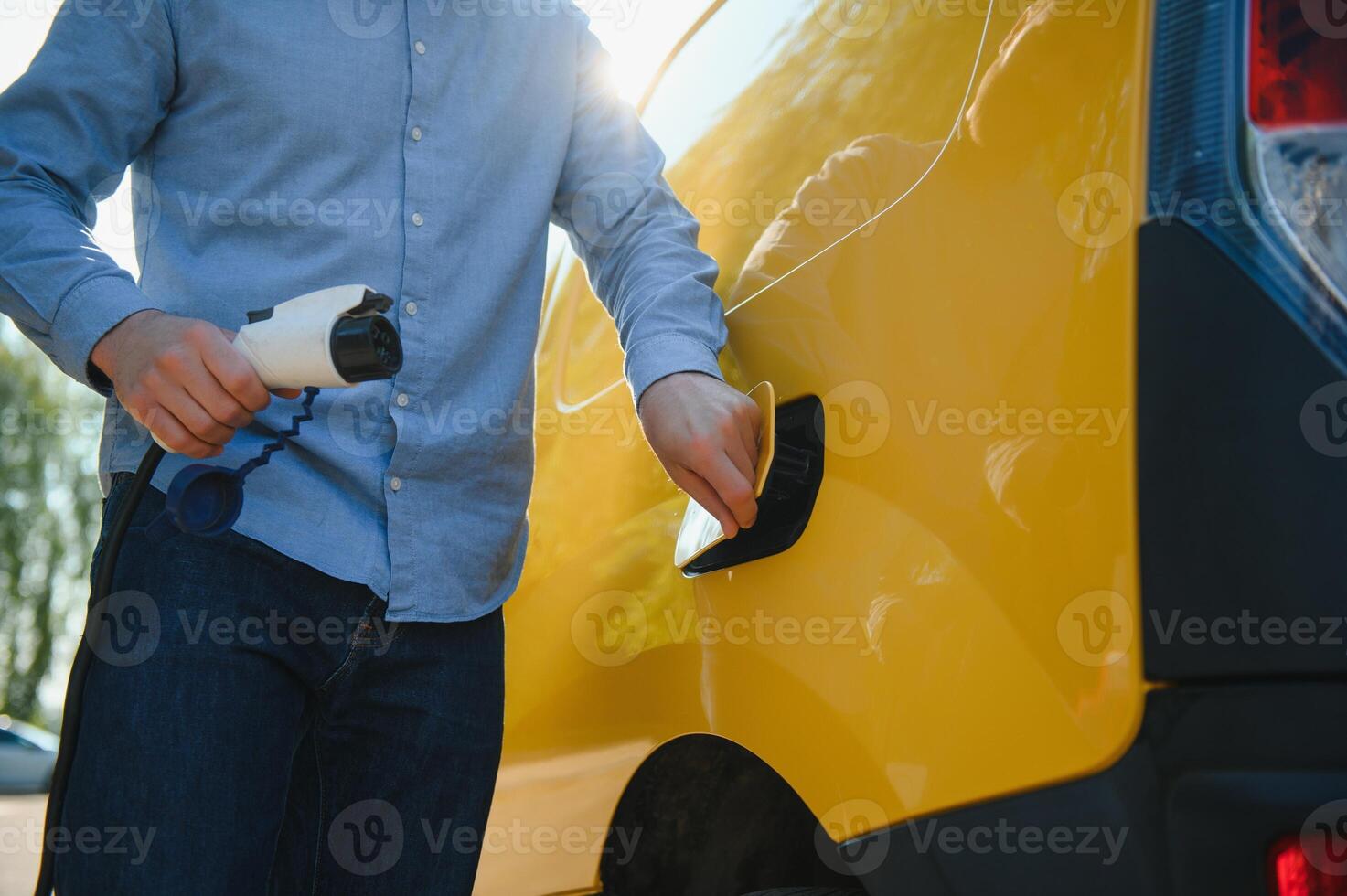 Smiling man unplugging the charger from the car photo