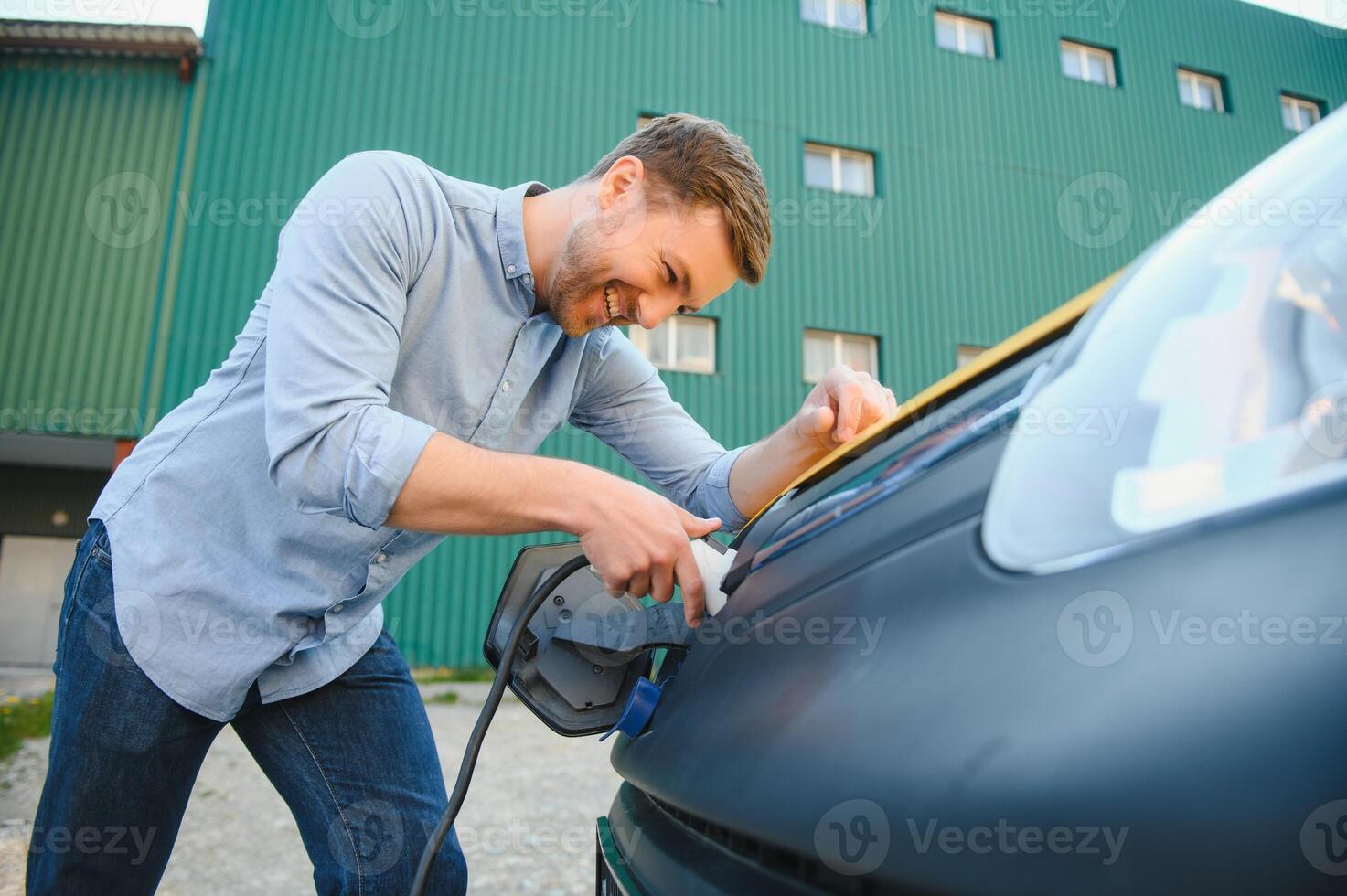 Smiling man unplugging the charger from the car photo