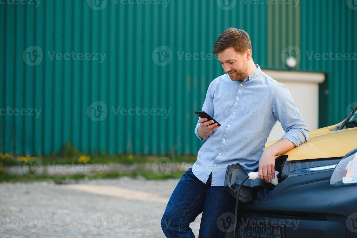 Smiling man unplugging the charger from the car photo