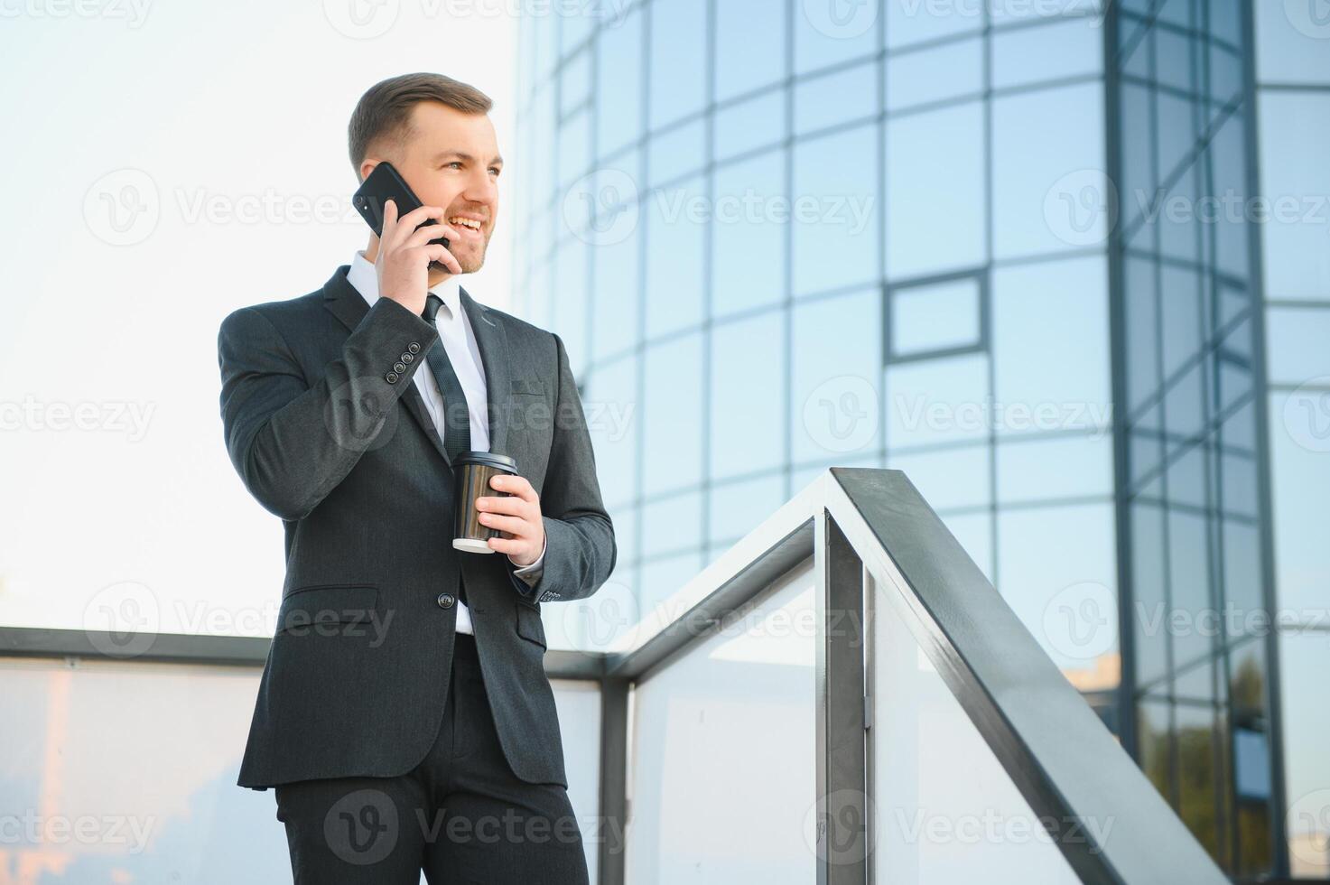 Bearded businessman in formal suit on break using mobile phone use smartphone. business man standing outside on modern urban city street background with coffee cup in downtown outdoors. copy space photo