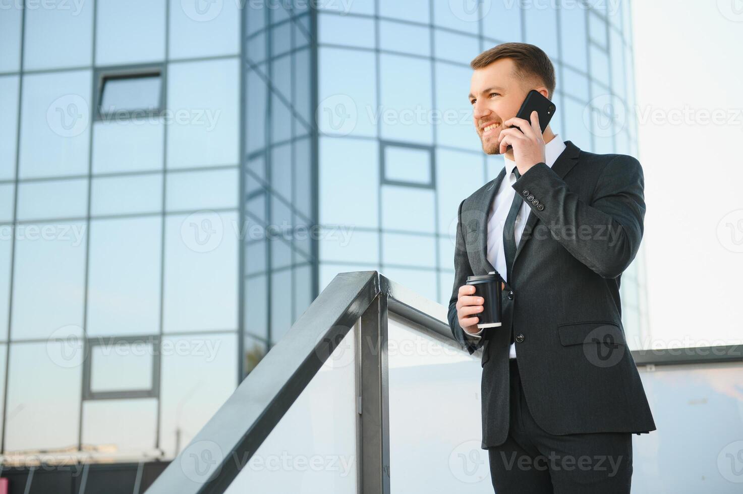 Bearded businessman in formal suit on break using mobile phone use smartphone. business man standing outside on modern urban city street background with coffee cup in downtown outdoors. copy space photo
