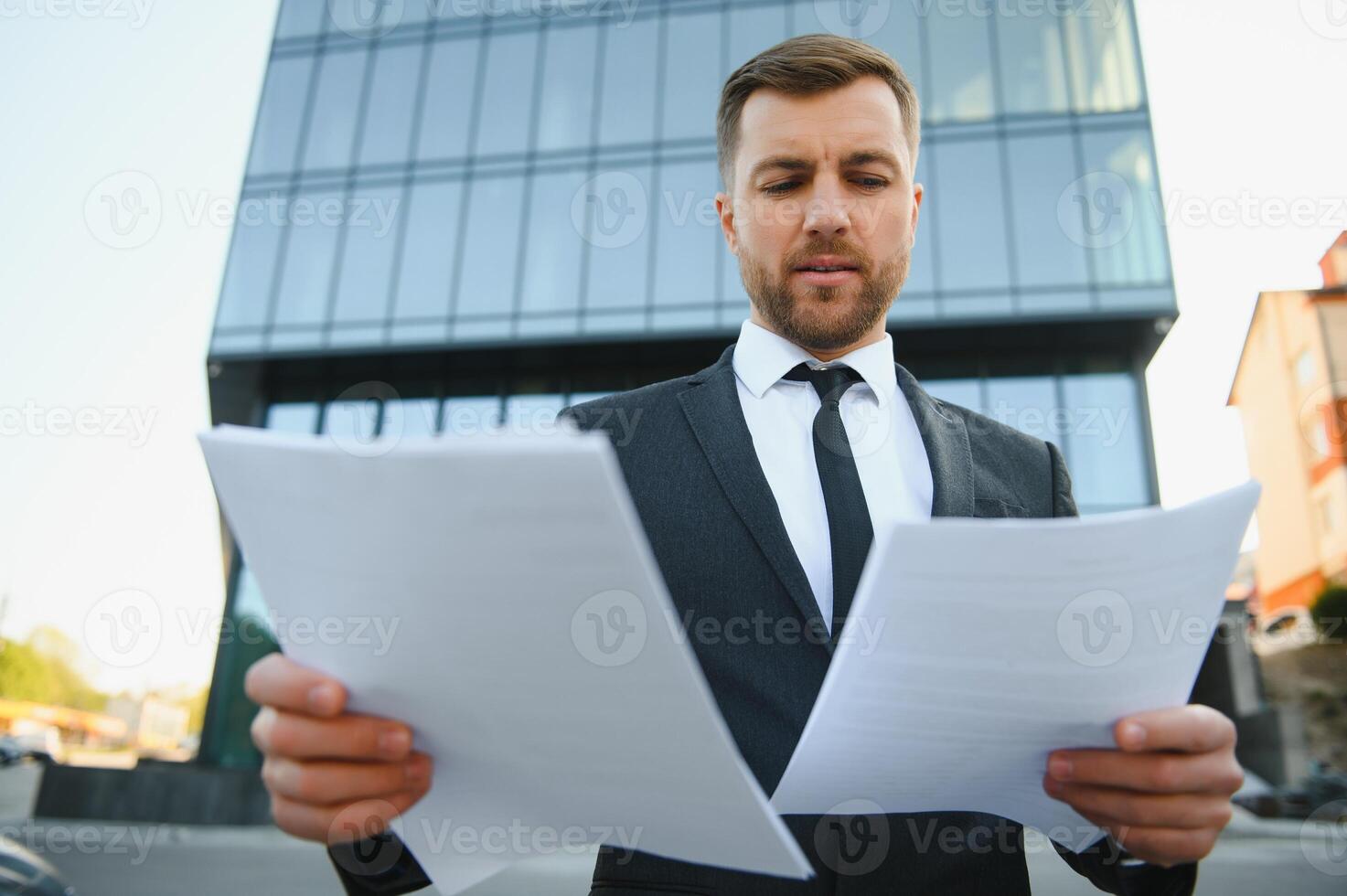 Portrait of young handsome manager wearing suit, holding business documents. photo