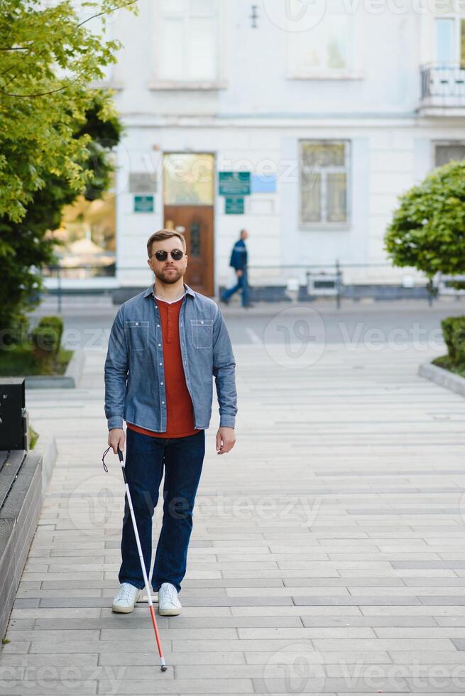 Blind man. People with disability, handicapped person and everyday life. Visually impaired man with walking stick. photo