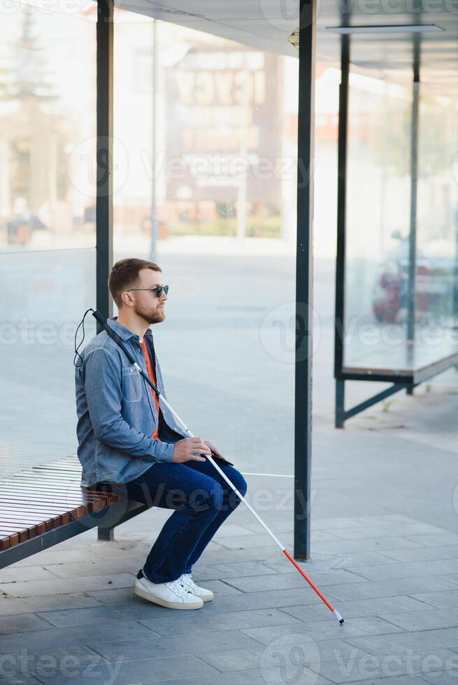 Blinded man waiting for bus at a bus station photo