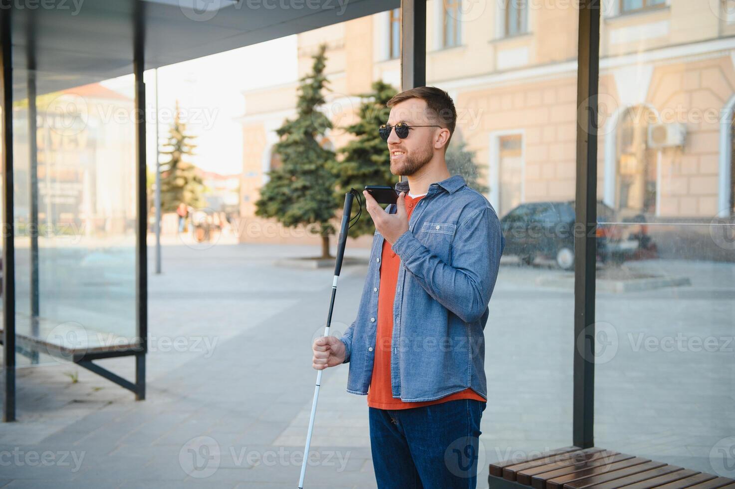 Young blinded man using phone and sending voice message photo