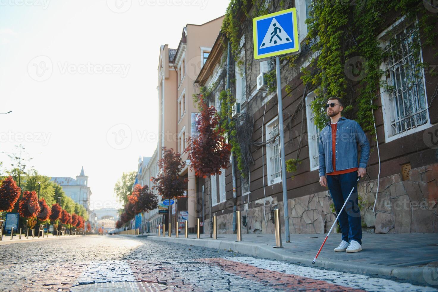 Blind person with white cane crossing street in city, closeup photo
