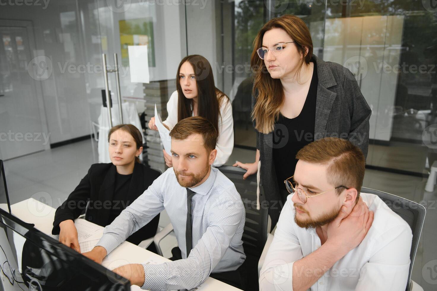 Smiling business people sitting at a desk in front of a laptop computer photo