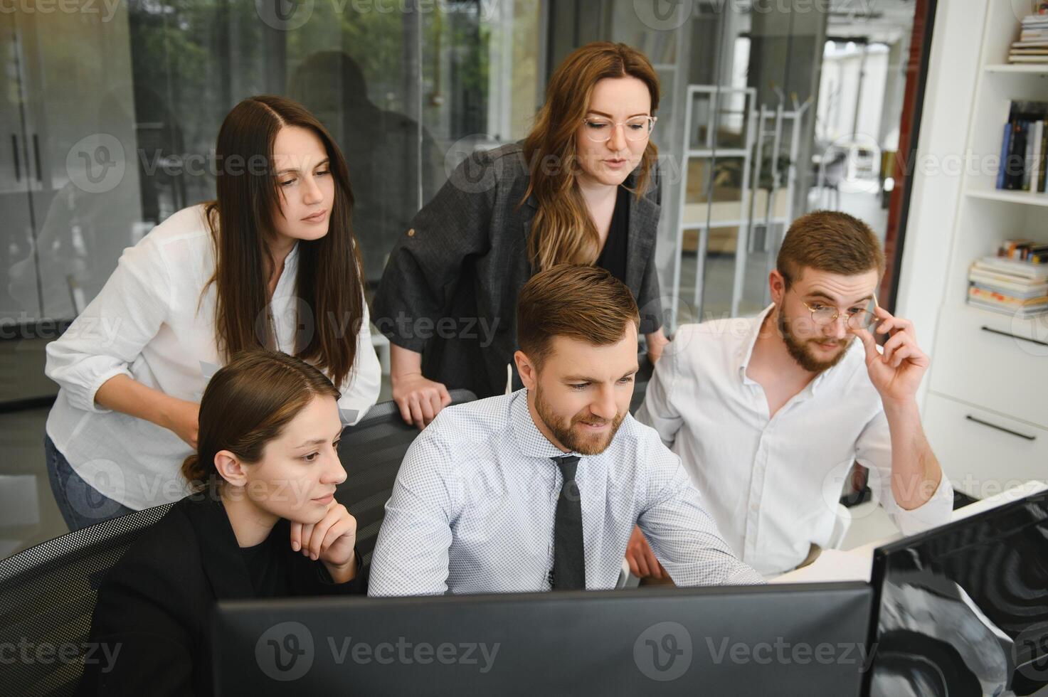 Smiling business people sitting at a desk in front of a laptop computer photo