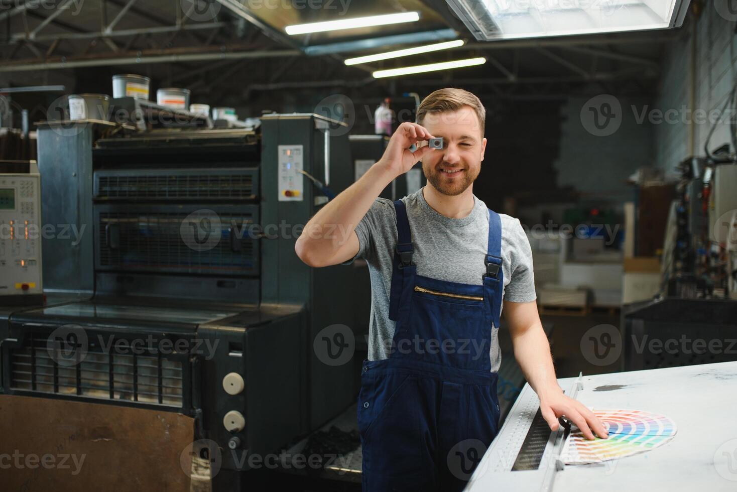 Portrait of production line worker controlling manufacturing process of modern packaging industrial machine in printing factory photo