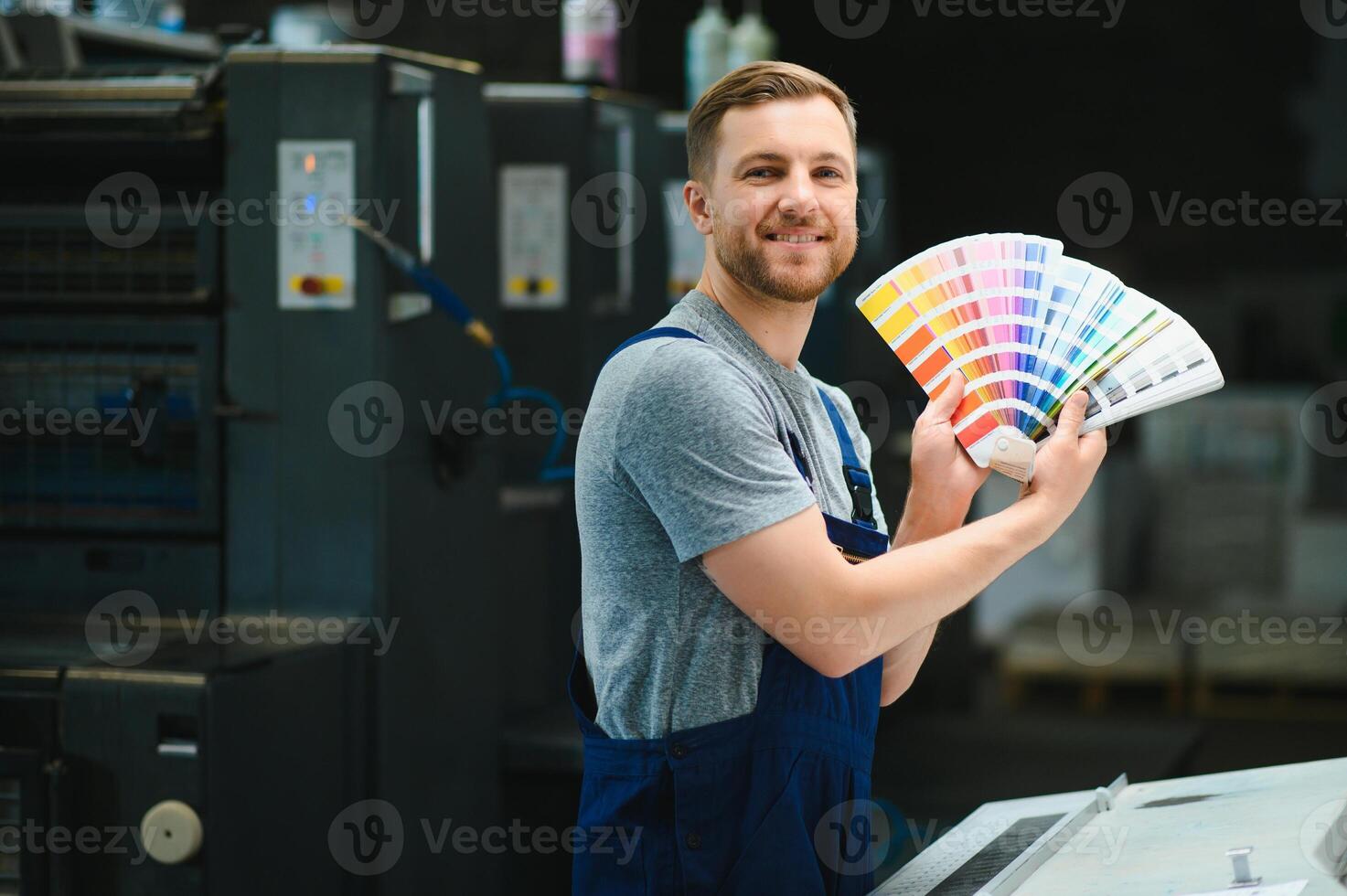 Man working in printing house with paper and paints photo