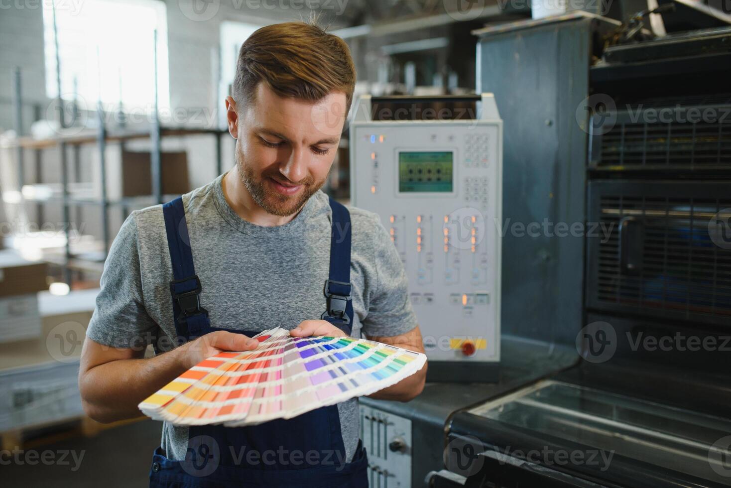 Portrait of worker at control room checking print quality at printing house. photo