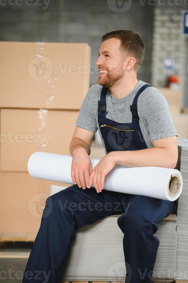 Portrait of production line worker controlling manufacturing process of modern packaging industrial machine in printing factory photo