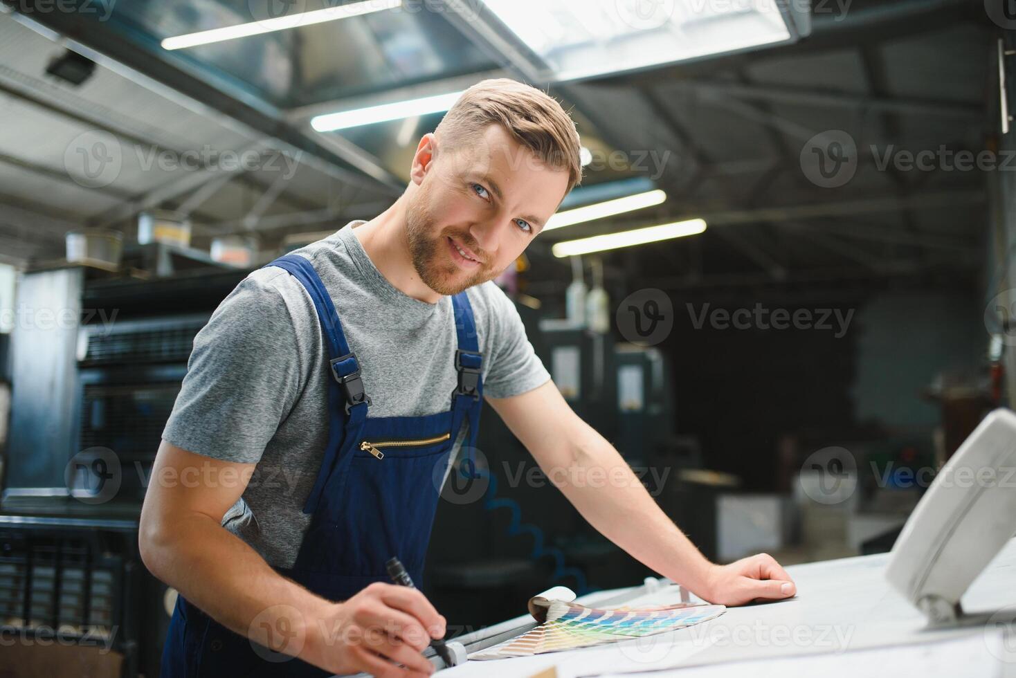 Man worker measuring printing color with spectrometer on the operating desk of the printing plant photo