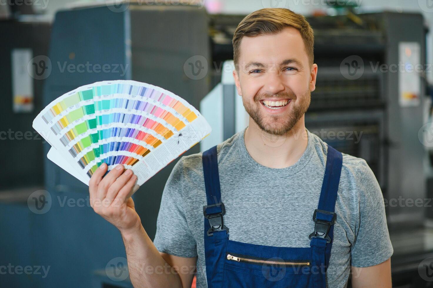 Portrait of production line worker controlling manufacturing process of modern packaging industrial machine in printing factory photo