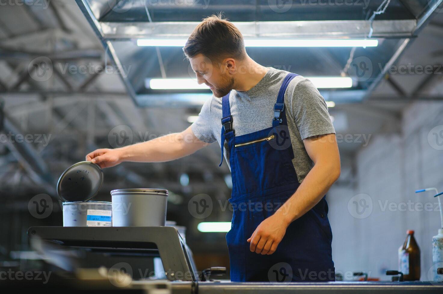 Man working in printing house with paper and paints photo