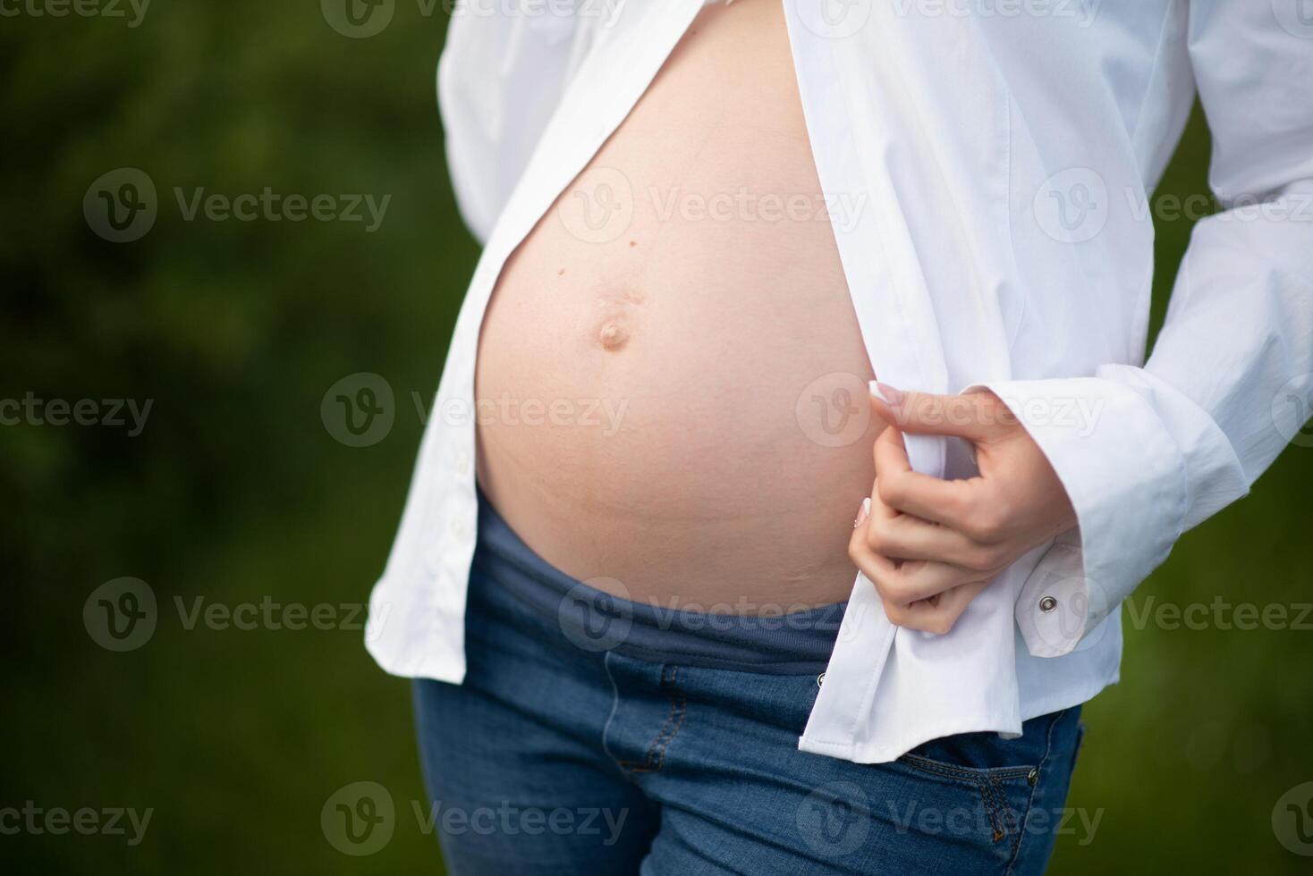 Close-up of pregnant woman with hands on her belly on nature background. photo