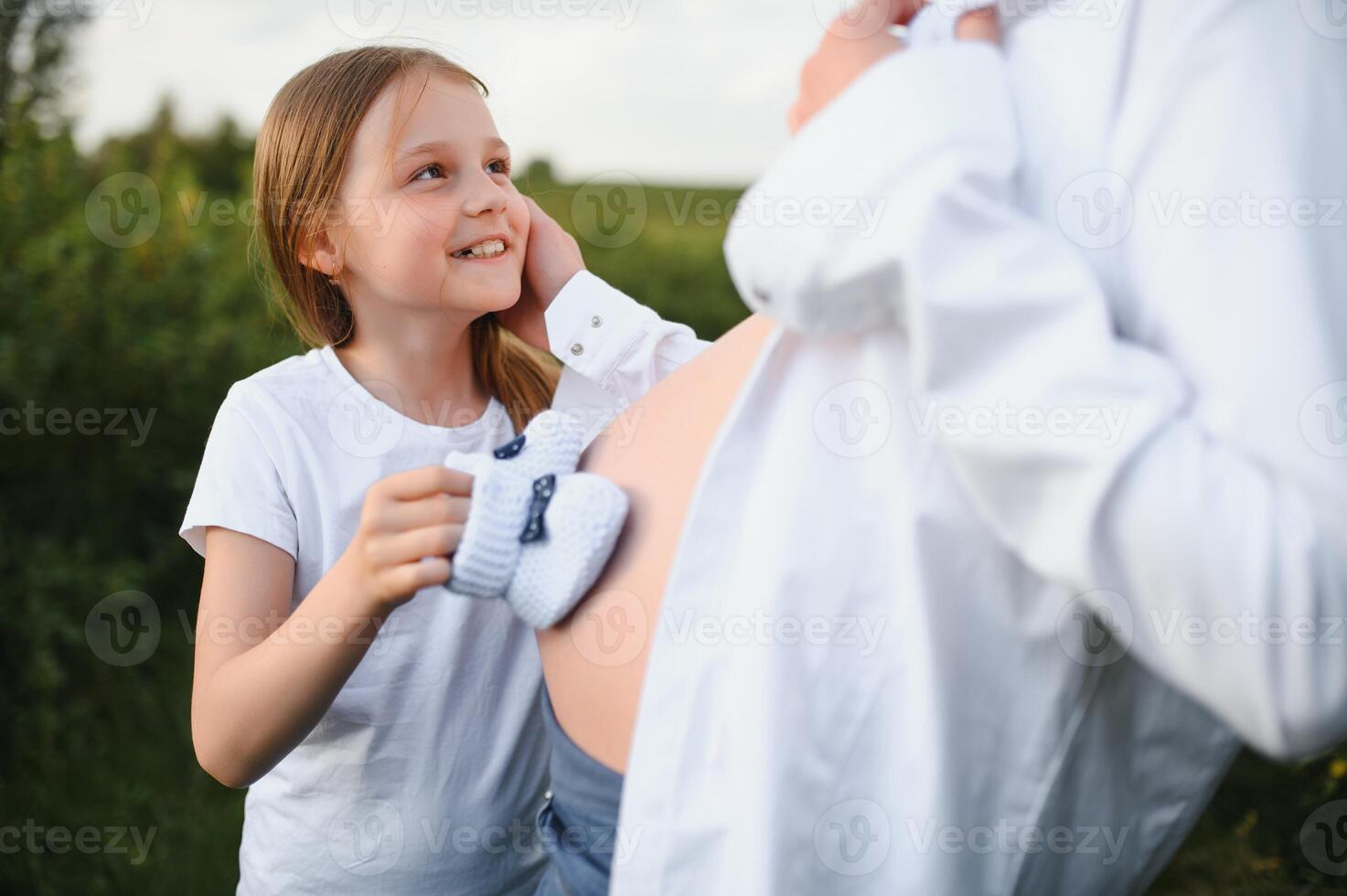 Pregnant woman and her daughter in the park at sunset. A happy family. photo
