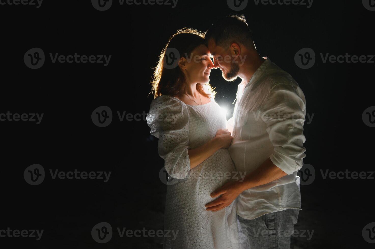 Happy Pregnant Couple. Mother and Father Love expecting Baby during Pregnancy. Family waiting Child Birth over Black night Background photo