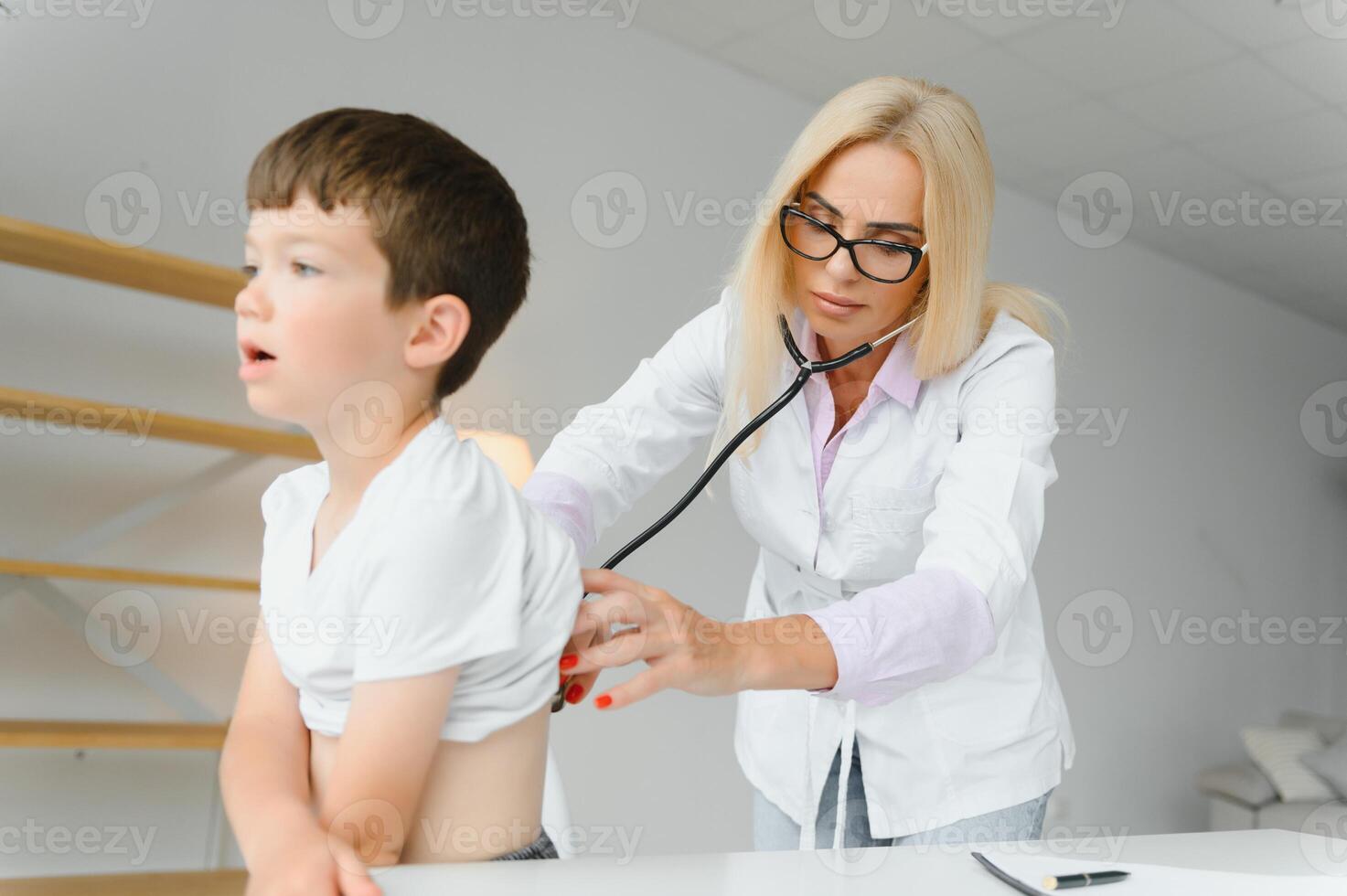 Pediatrician doctor examining little boy's heart beat and lungs to check for problems photo