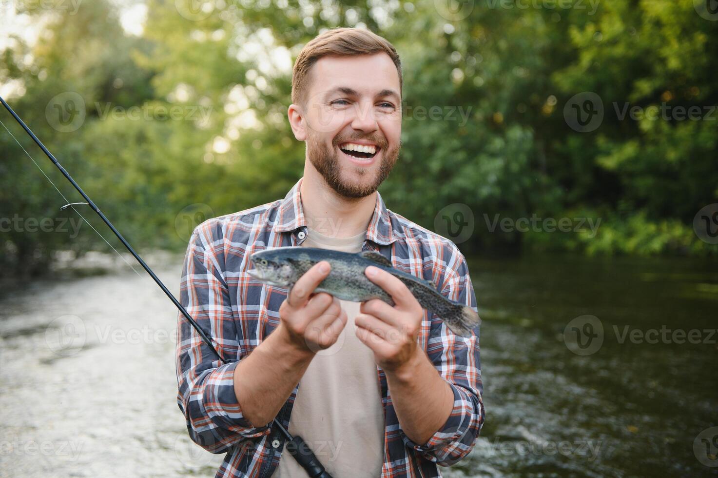Man with fishing rod, fisherman men in river water outdoor. Catching trout fish in net. Summer fishing hobby photo