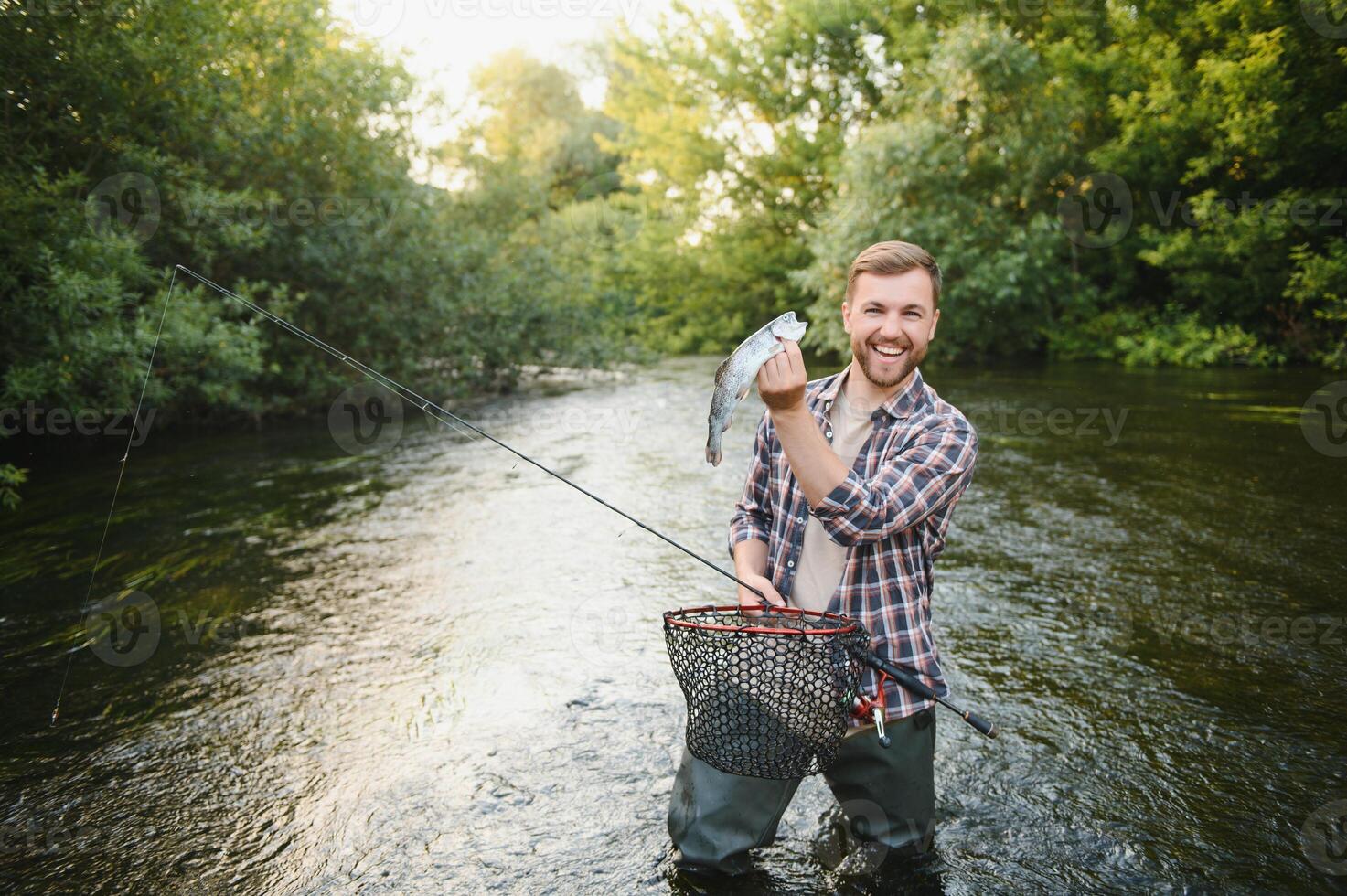Fisherman catches a trout on the river in summer photo