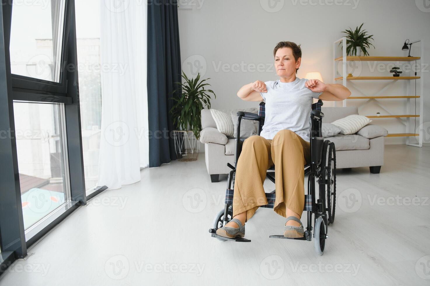 Woman in wheelchair working out in living room photo