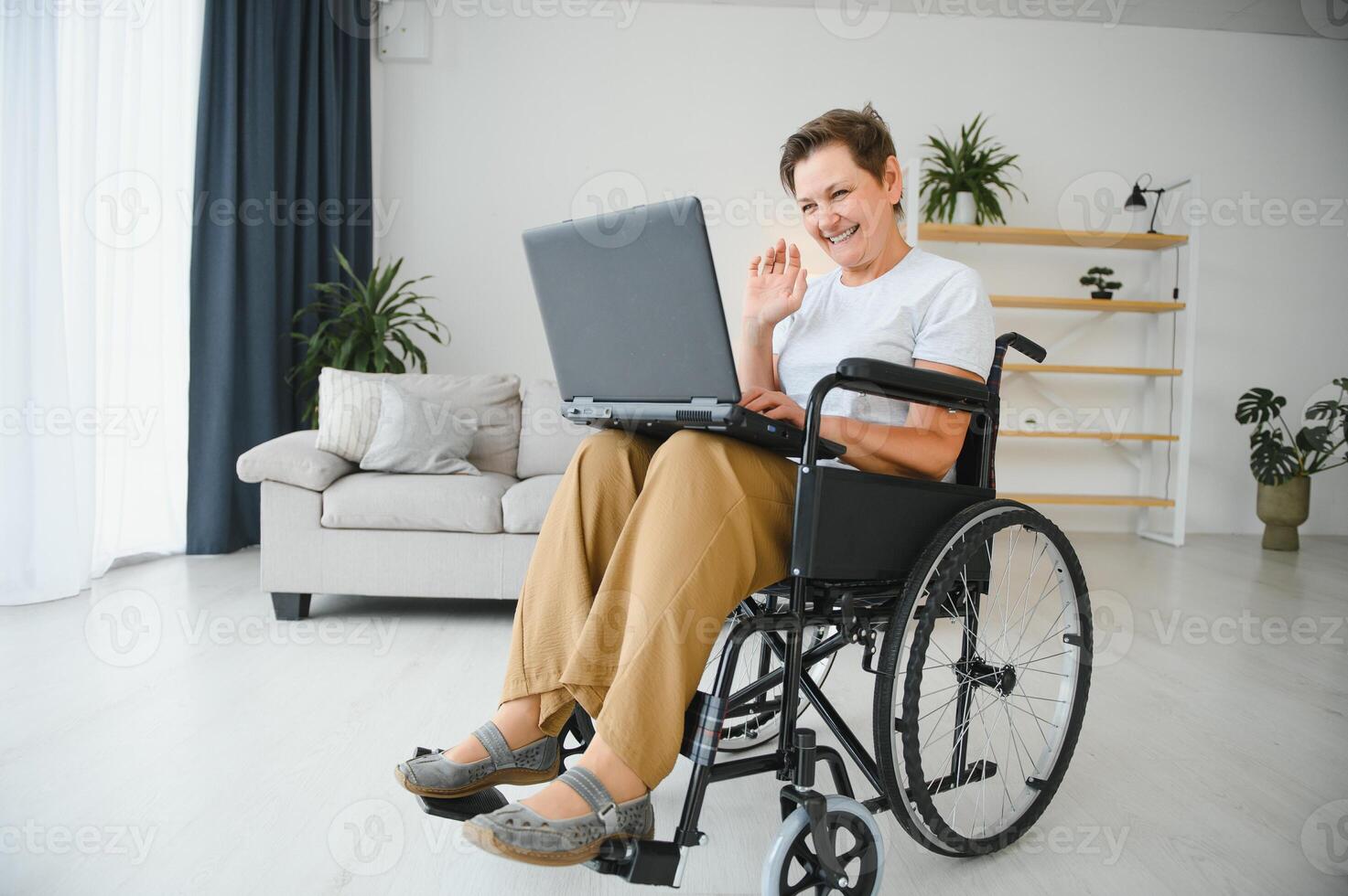 Middle age disabled woman having call sitting on wheelchair at home. photo