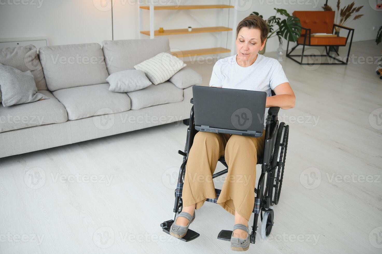 Middle age disabled woman having call sitting on wheelchair at home. photo