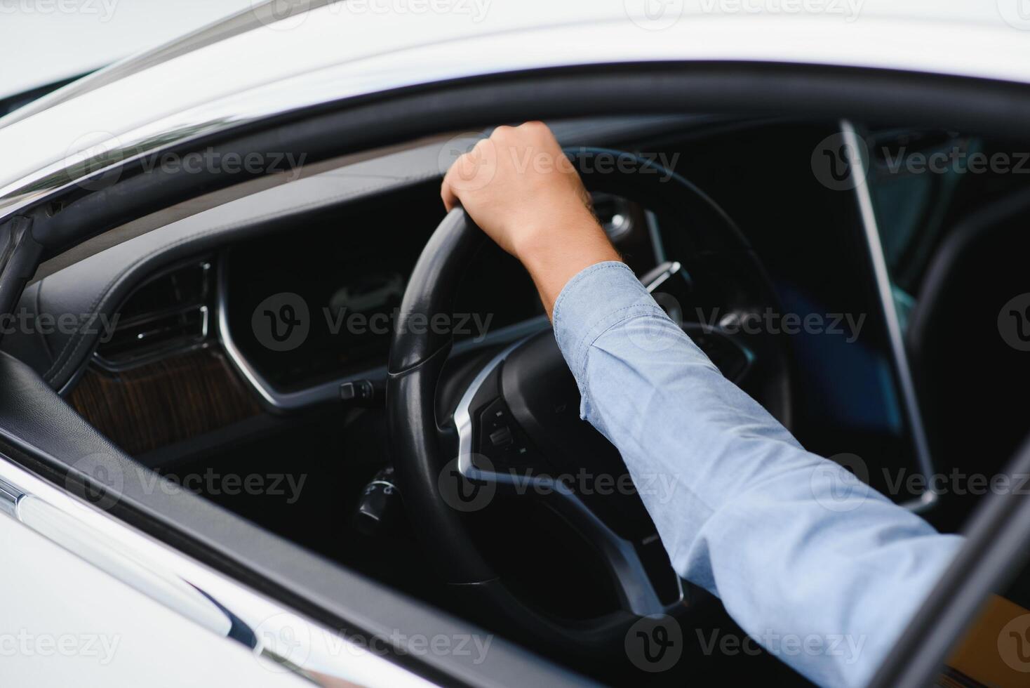 Businessman holding steering wheel while driving modern electric car on the street road. Confident man driving expensive car. Driver Turning Steering Wheel In Luxurious Auto On Trip photo