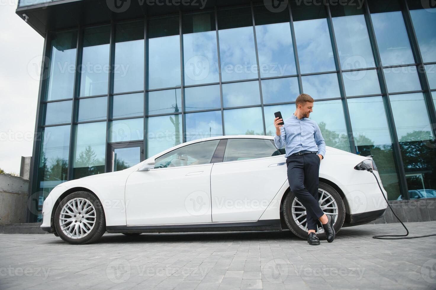 Man charges an electric car at the charging station photo