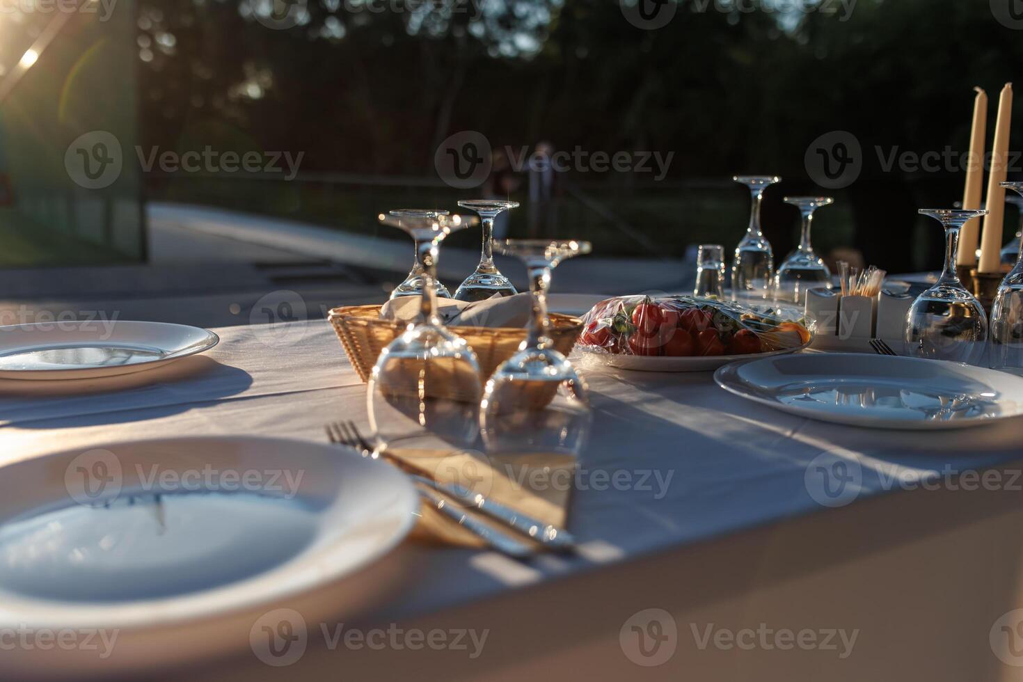 empty wine glasses on banquet served table in open air in rays of setting sun photo