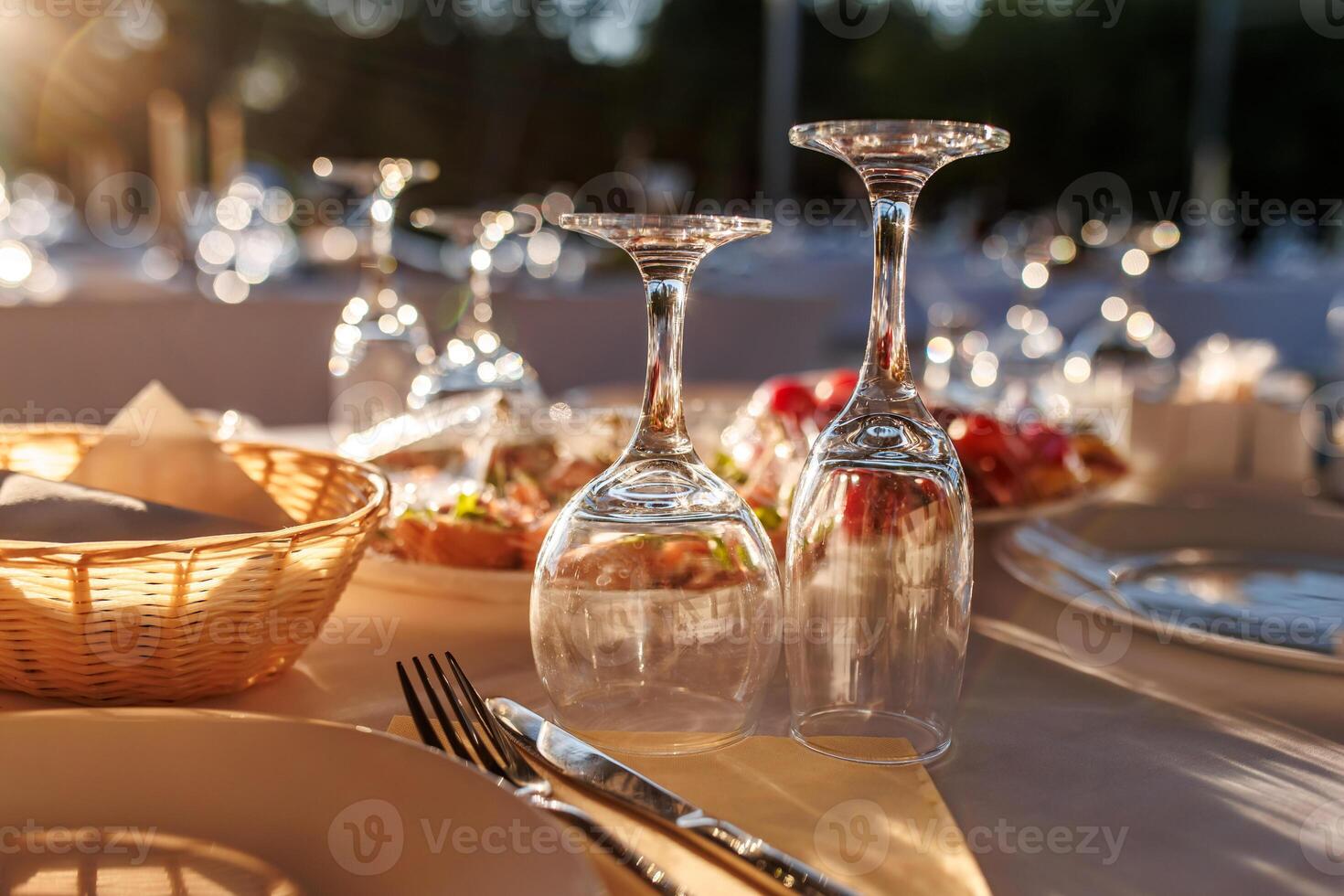 empty wine glasses on banquet served table in open air in rays of setting sun photo