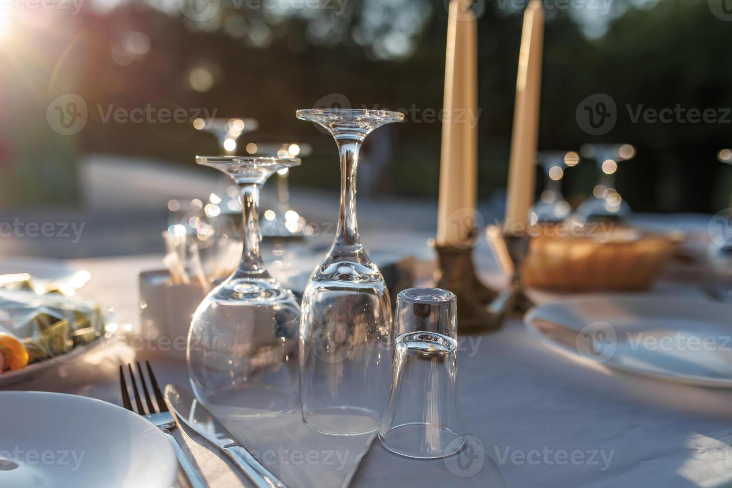 empty wine glasses on banquet served table in open air in rays of setting sun photo