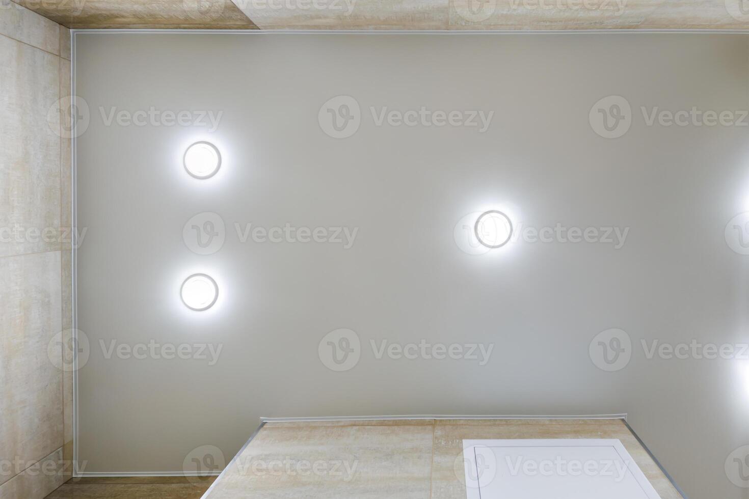 suspended ceiling with halogen spots lamps and drywall construction in empty room in apartment or house. Stretch ceiling white and complex shape. photo