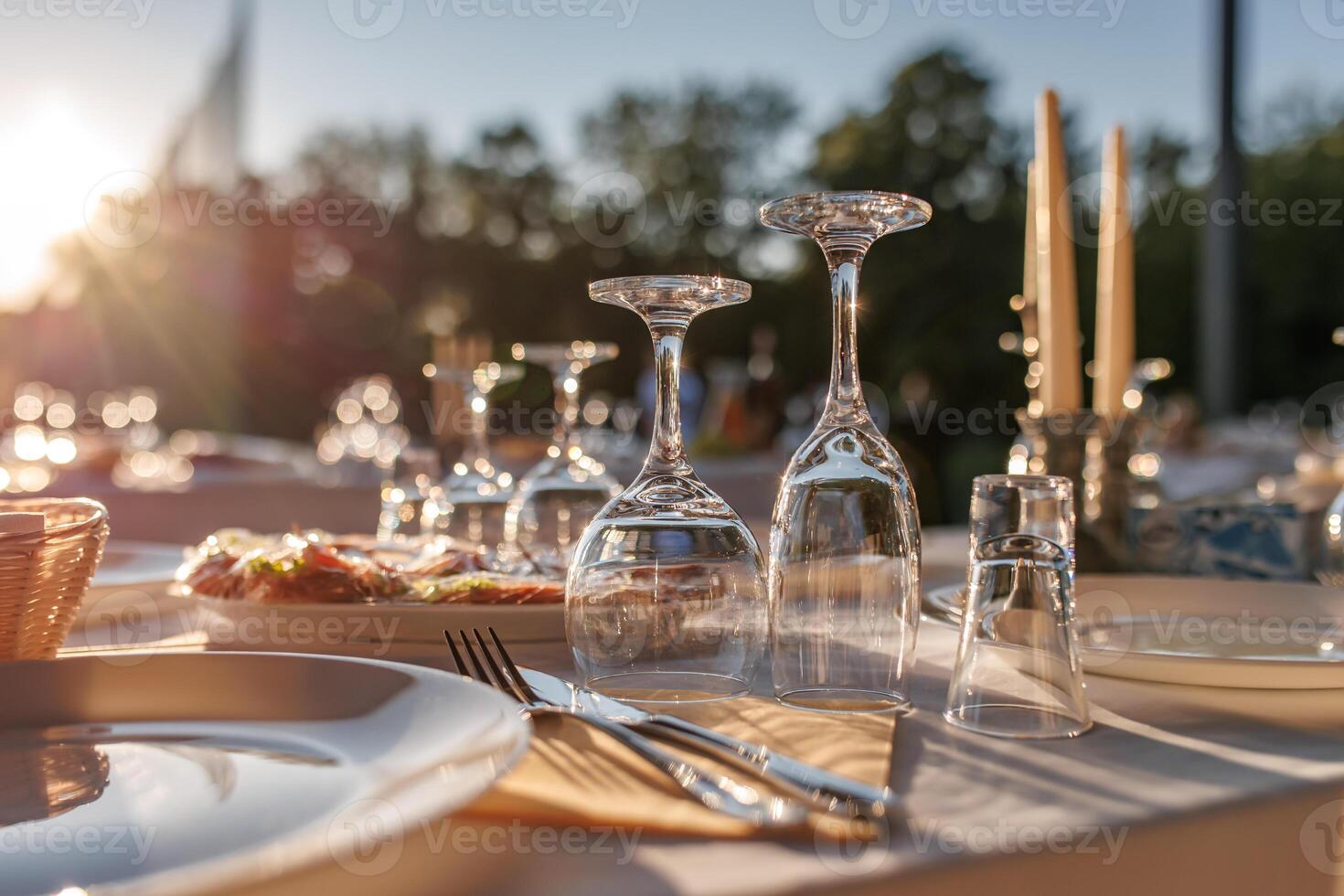 empty wine glasses on banquet served table in open air in rays of setting sun photo