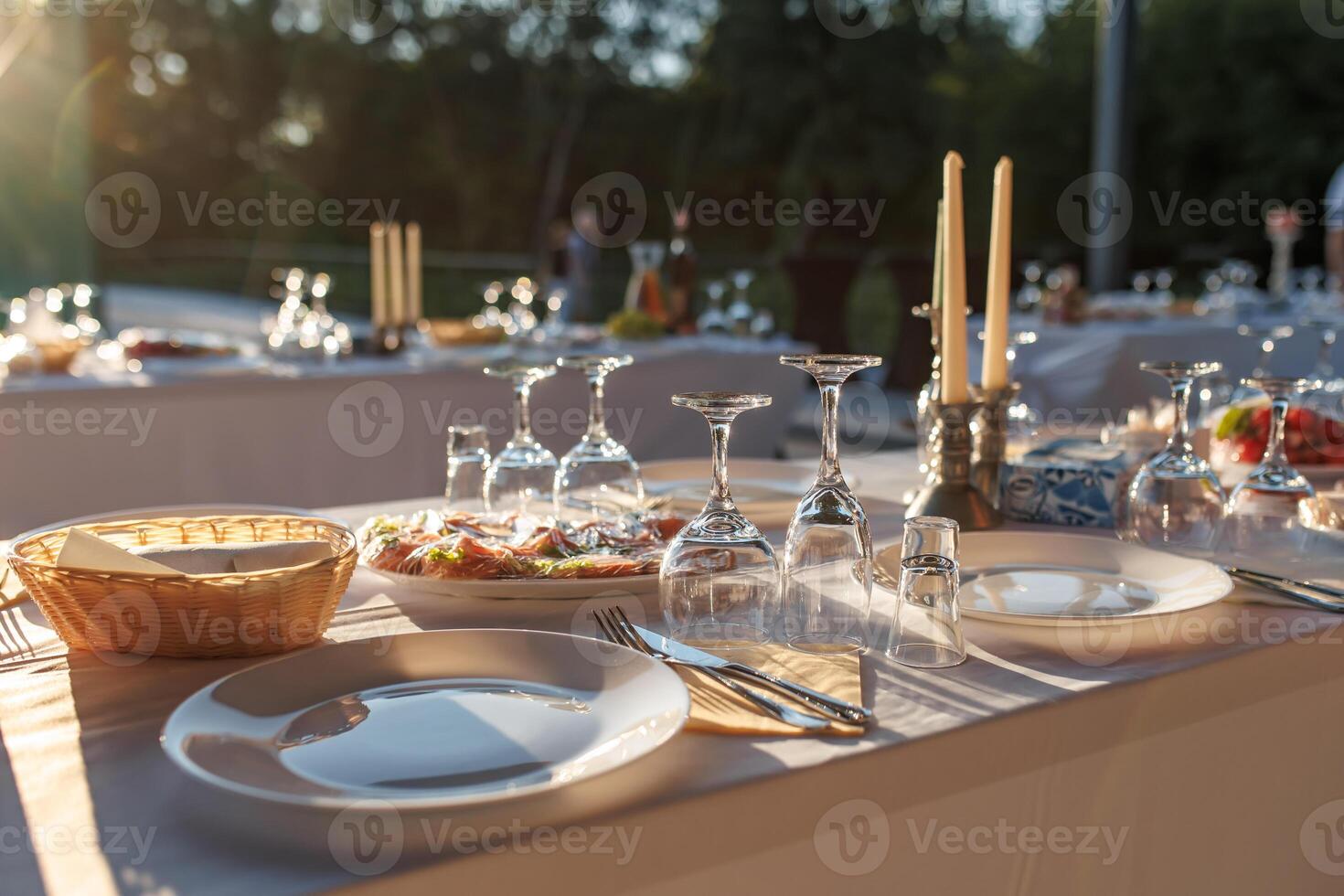 empty wine glasses on banquet served table in open air in rays of setting sun photo