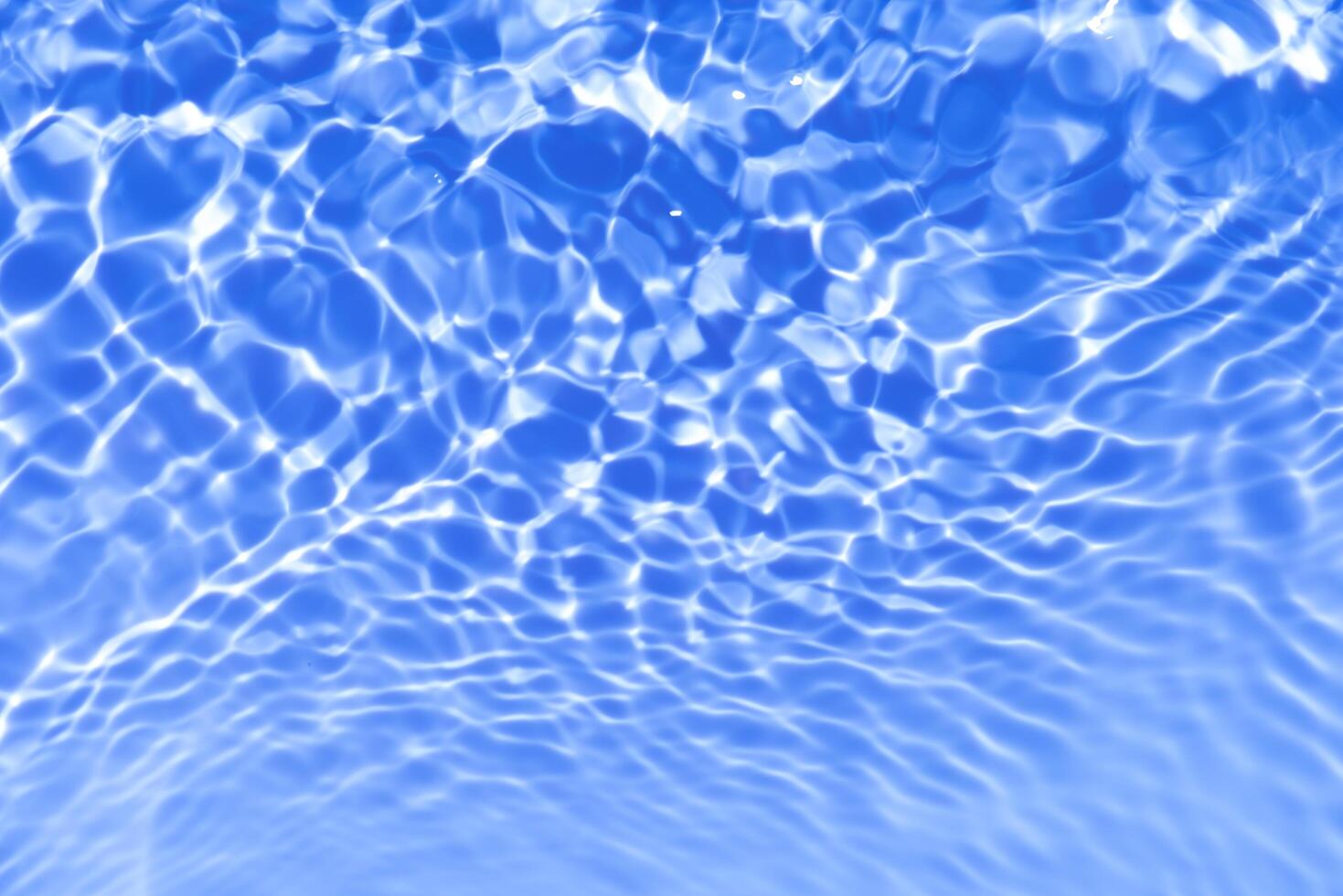 Blue water with ripples on the surface. Defocus blurred transparent blue colored clear calm water surface texture with splashes and bubbles. Water waves with shining pattern texture background. photo