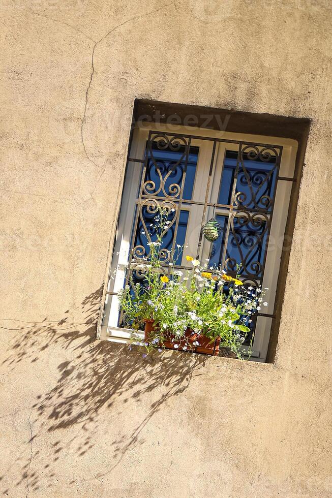 wall of a house with a window, flowers on the windowsill rustic style house facade photo