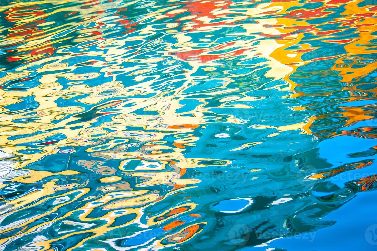 Colorful reflections on water creating an abstract pattern with vibrant hues of blue, yellow, red, and green. photo