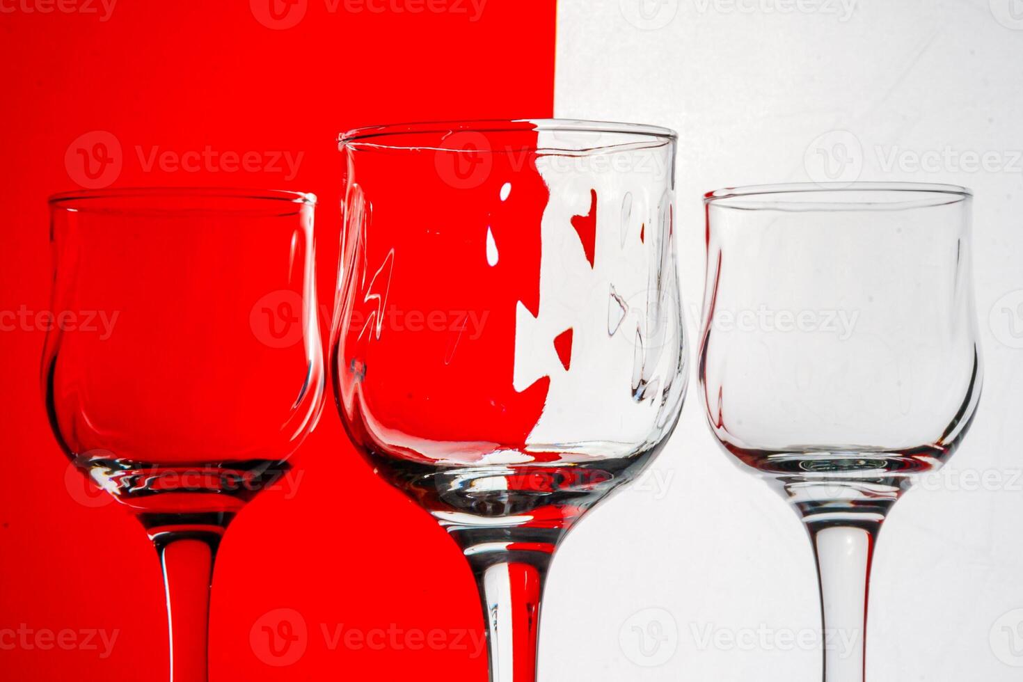 Three empty wine glasses with a red and white striped background. photo