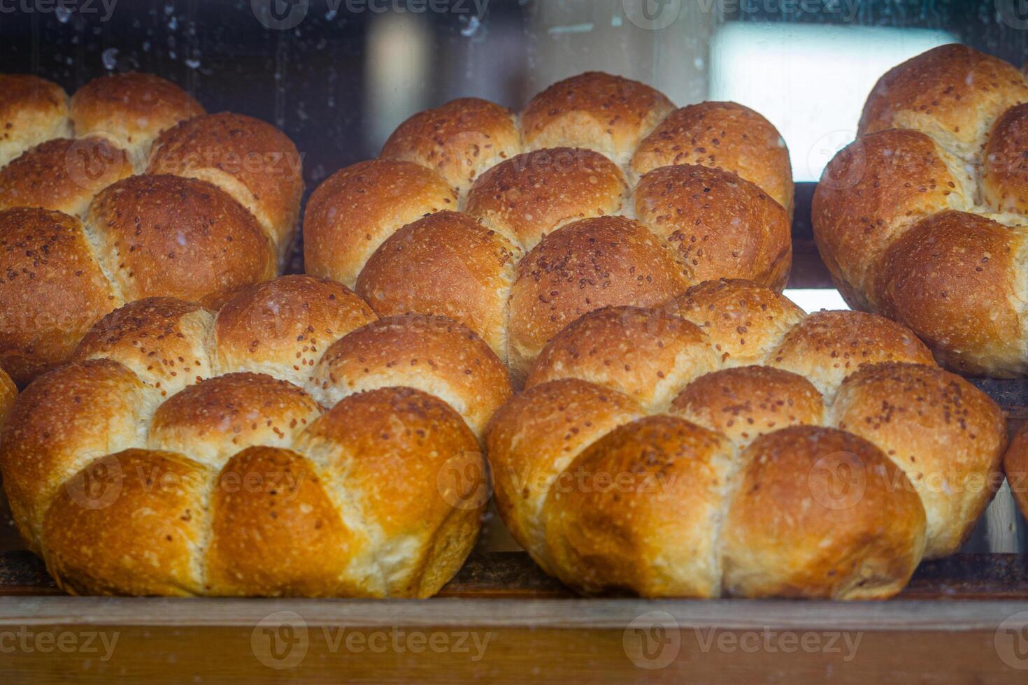 Freshly baked flower shaped bread rolls with a golden crust displayed in a bakery window, in Turkey photo