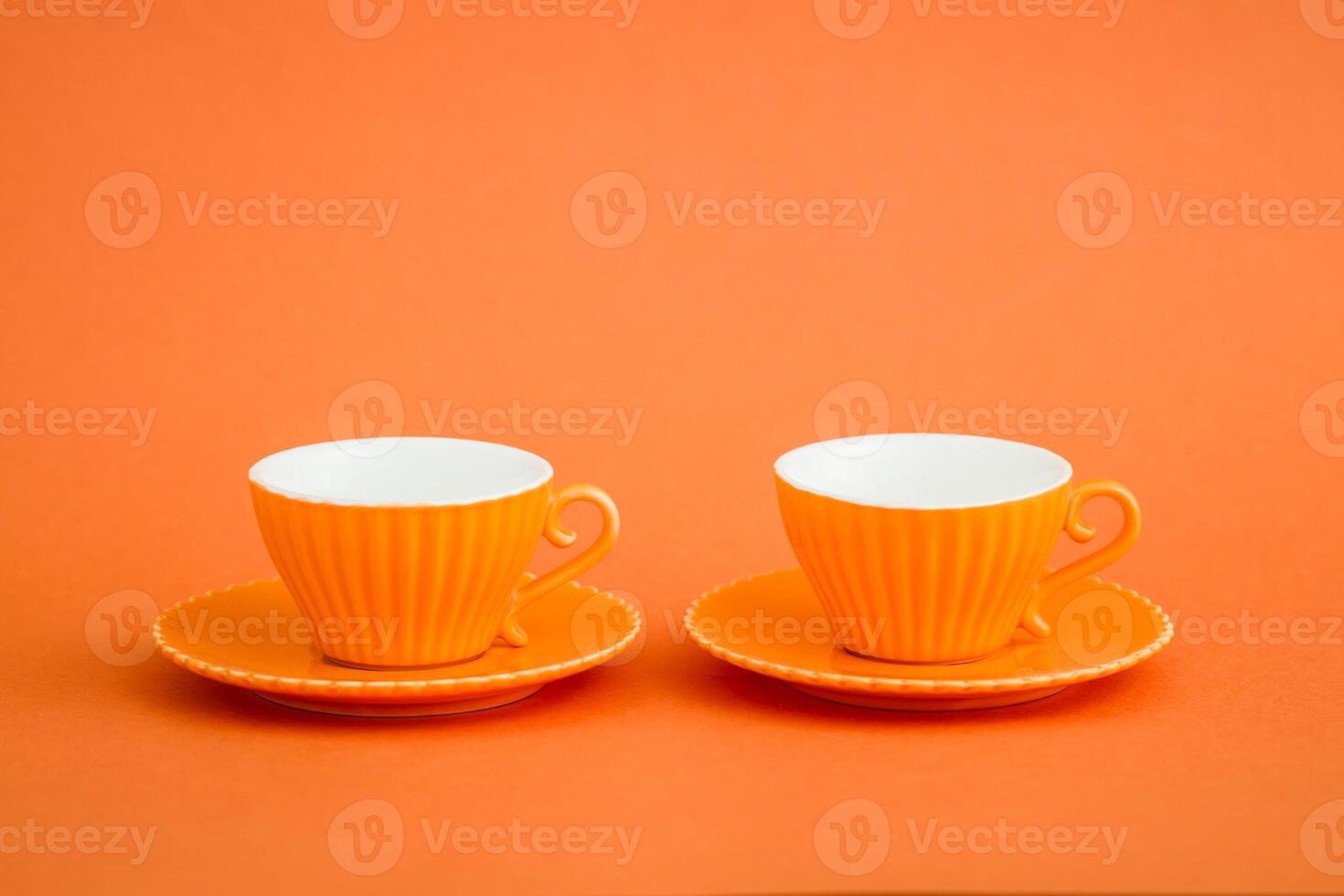 Array of orange coffee cups against vibrant orange background. photo