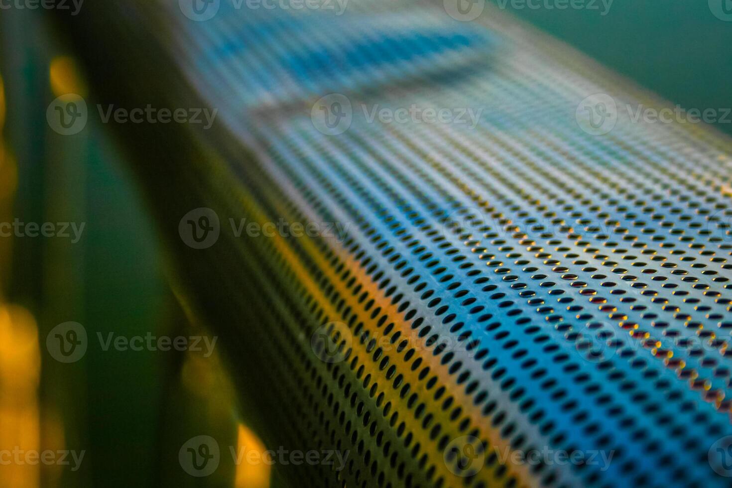 Close up of a perforated metal surface with a blurred background, showcasing the texture and pattern of the holes. photo