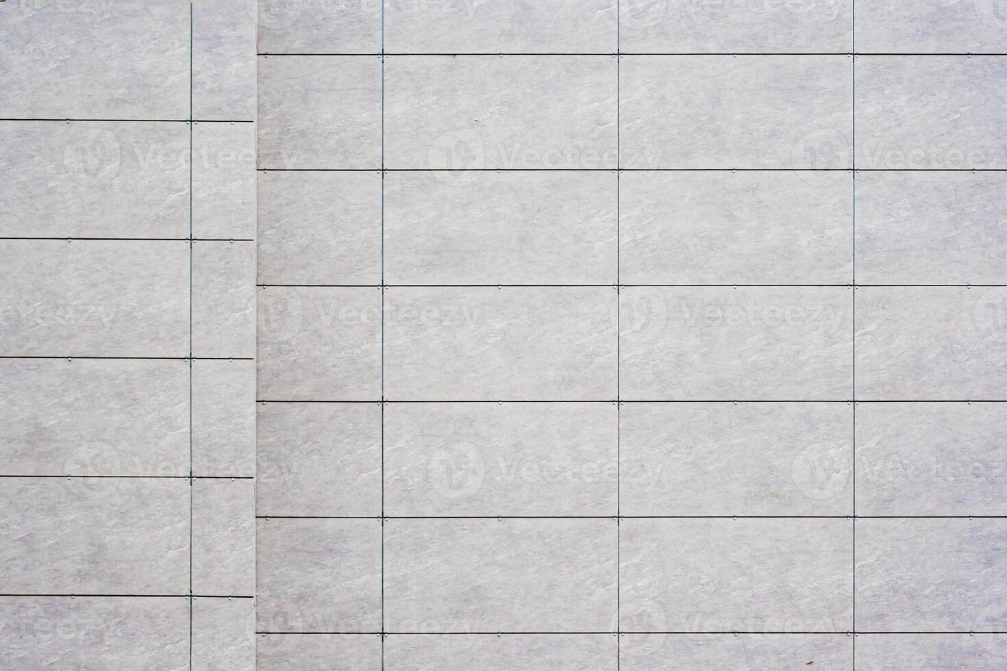 Close up of a tiled wall with a grid pattern, featuring light gray tiles and dark grout lines, as texture, background. photo