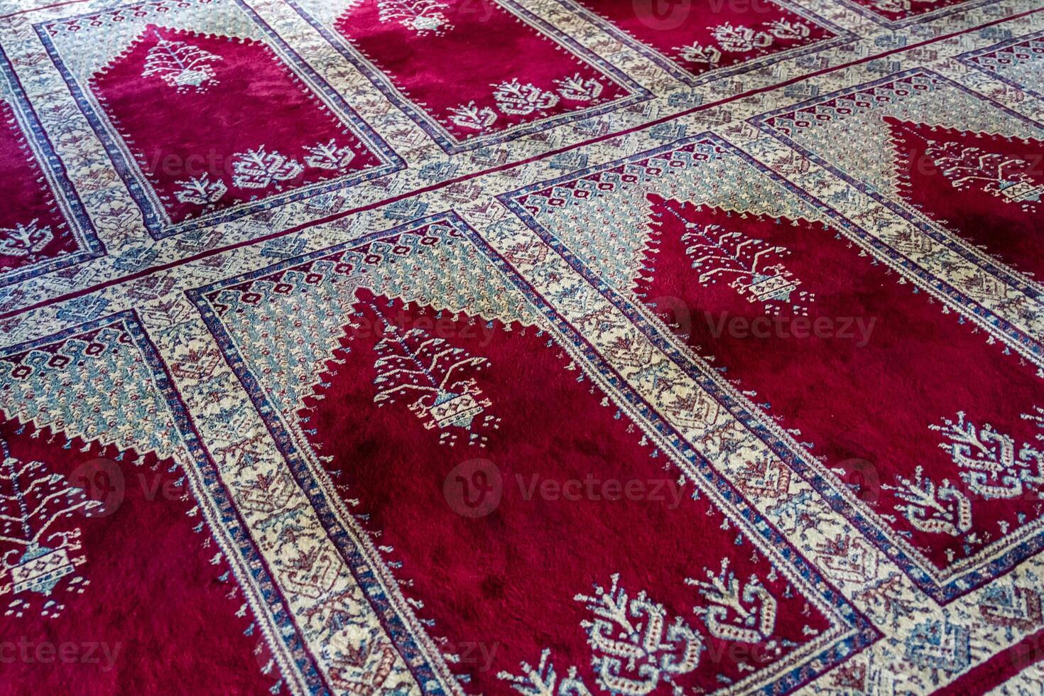 Close up of a traditional red and white patterned carpet with intricate designs, in a mosque, Turkey. photo