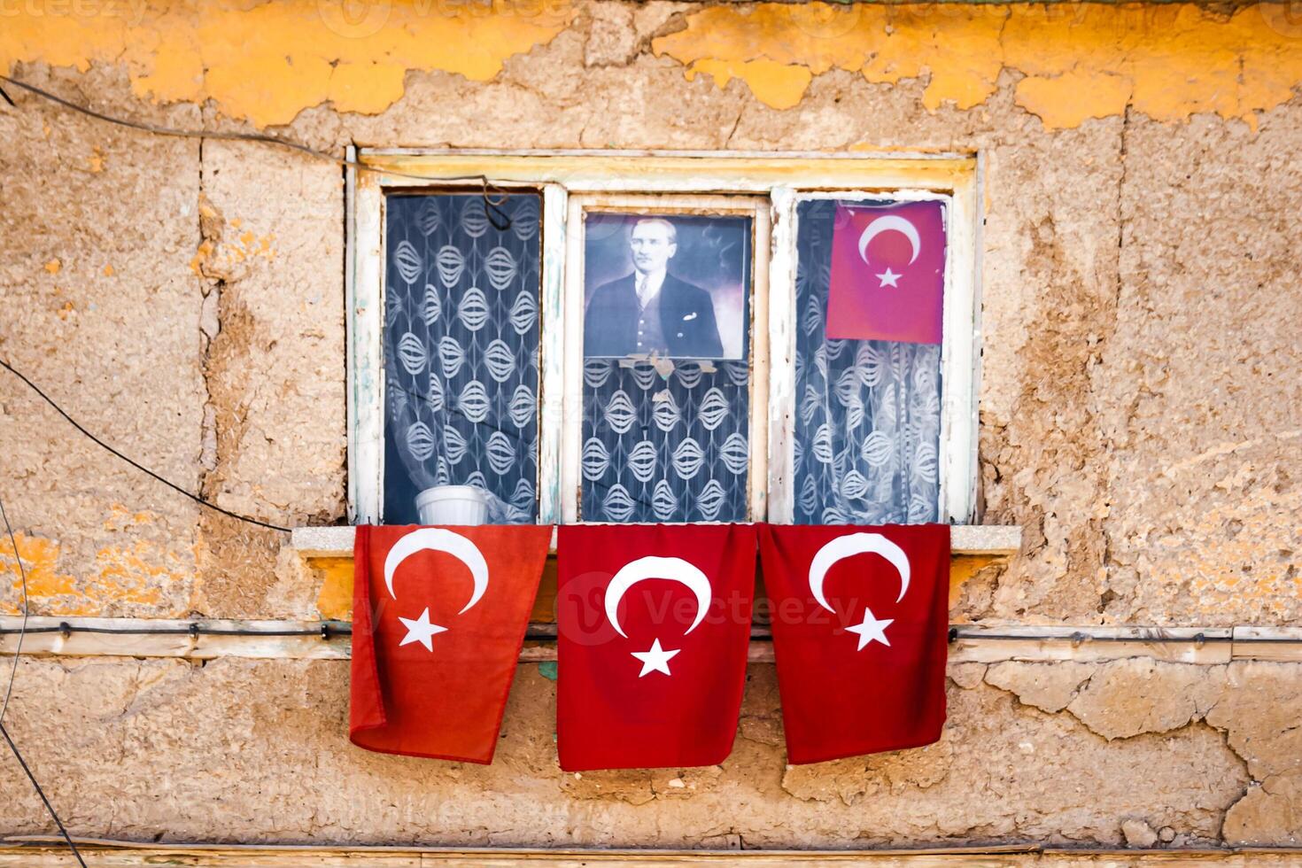 Window with Turkish flags hanging on and around it, set against an old, weathered yellow wall, in Turkey. photo