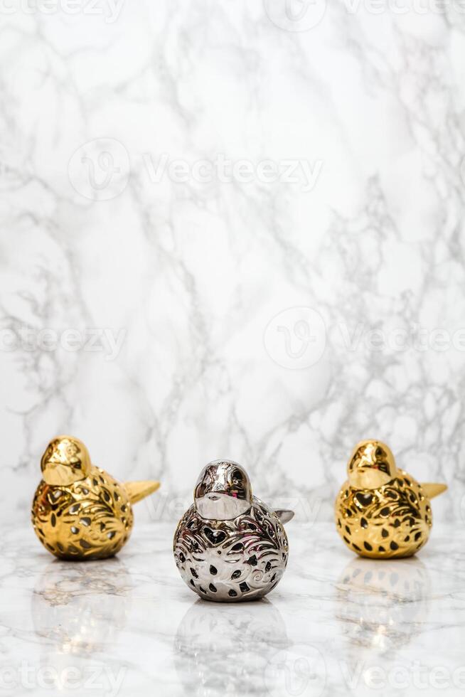 Golden and Silver Sparrow Figurines Arranged in a Row on a Marble Background with Copy Space photo