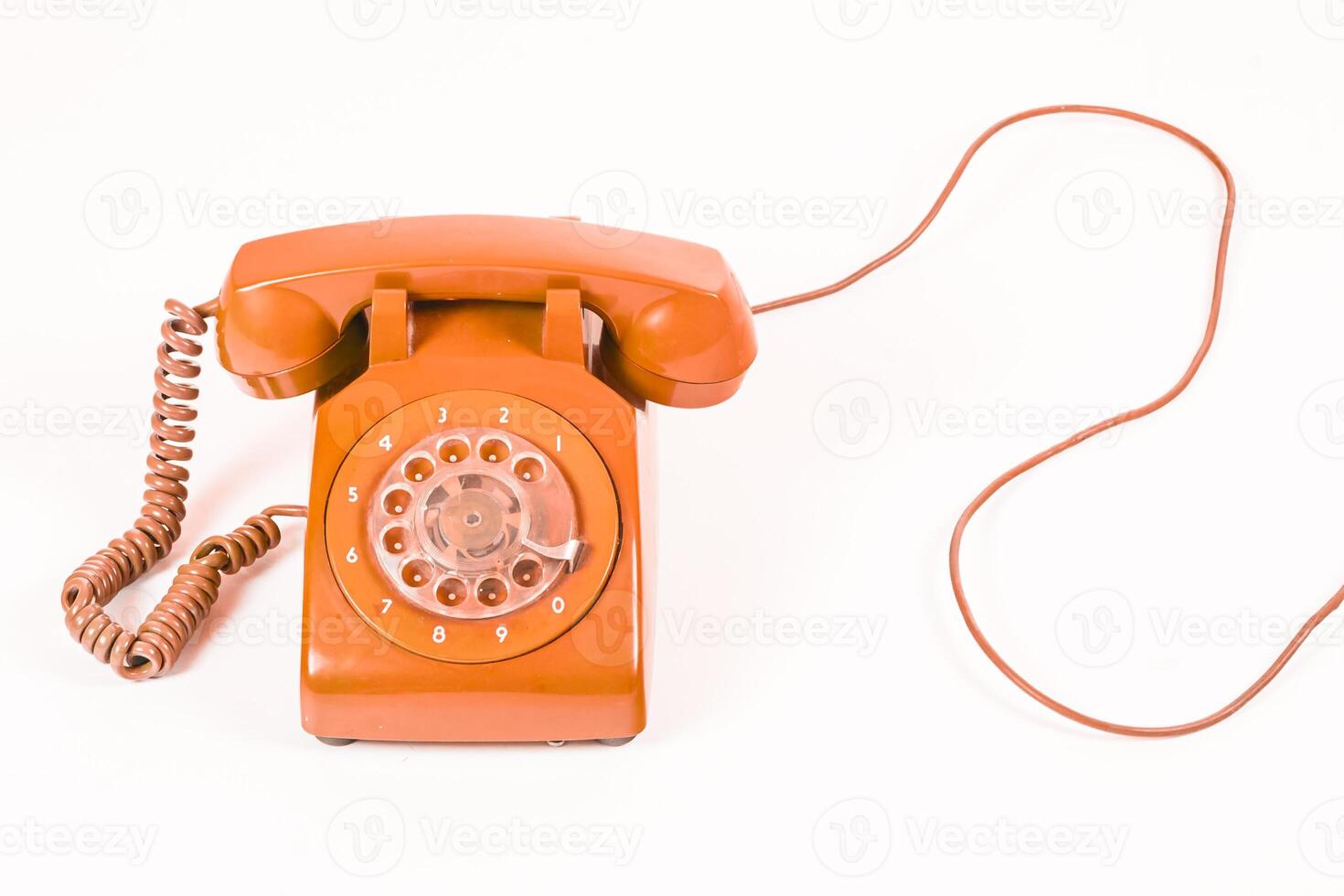 Vintage orange rotary dial telephone with a coiled cord, on a white background, studio shot. photo
