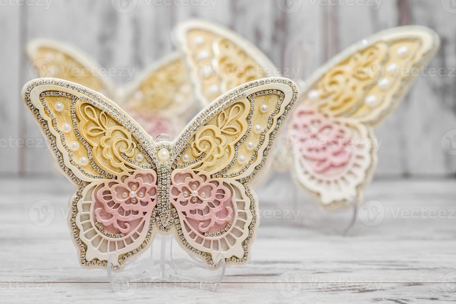 Decorative butterflies with ornaments and intricate design in pastel colors, displayed on a white wooden surface. photo