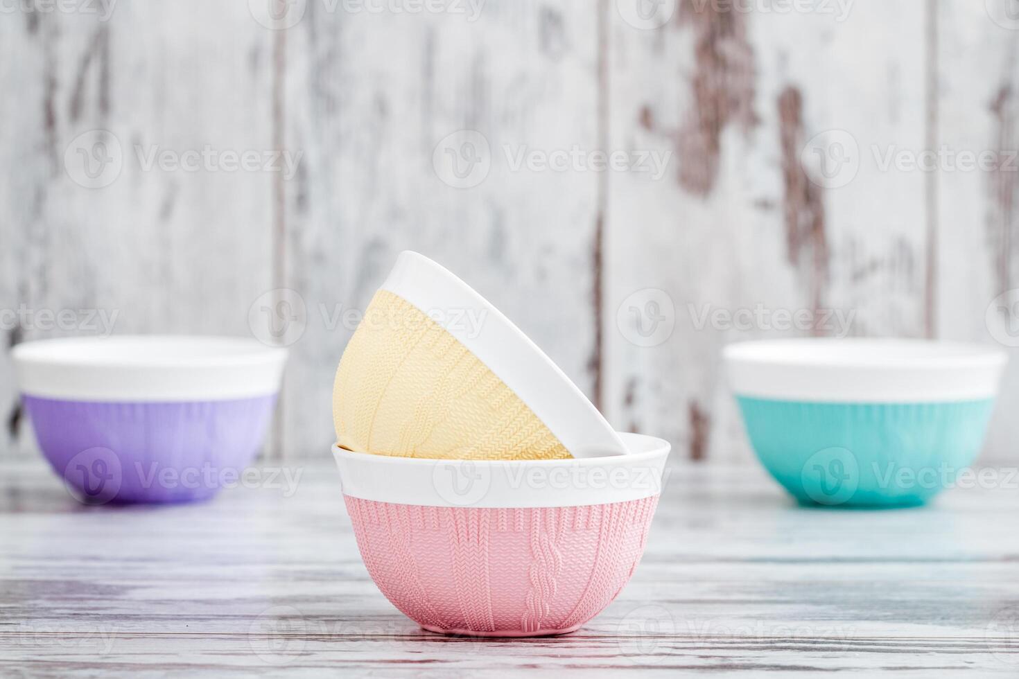 Colorful bowls with knitted patterns, stacked and arranged on a wooden surface with a rustic background. photo